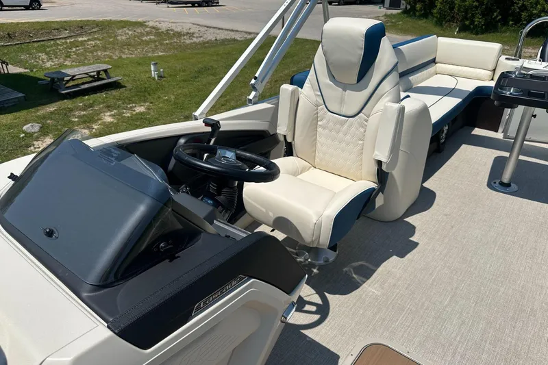 Slide: The Image of 2025 Tahoe 2585 boat interior with luxurious seating and steering wheel, parked outdoors. - 13