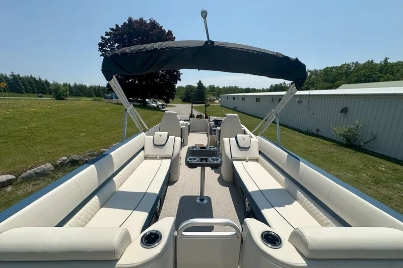 Slide: The Image of 2025 Tahoe 2585 pontoon boat with spacious seating and canopy, parked on grassy area. - 18