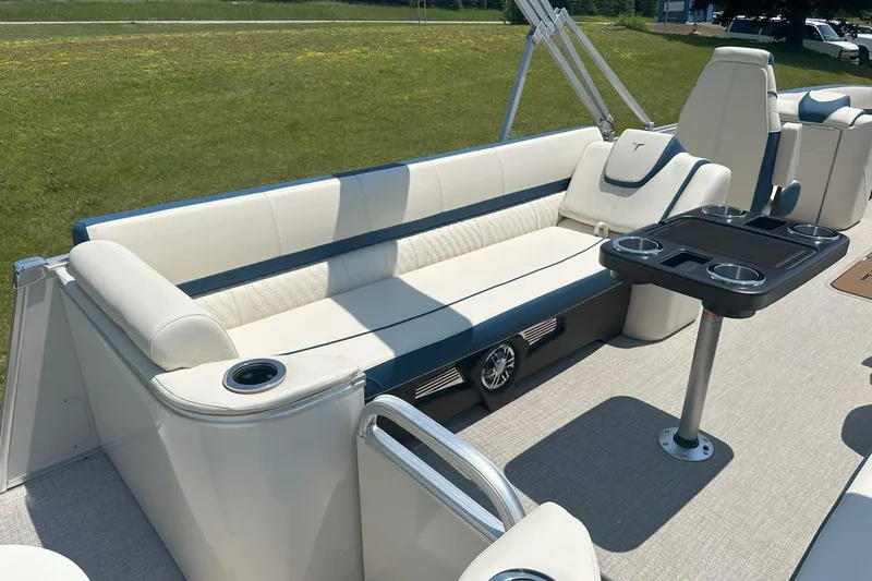Slide: The Image of 2025 Tahoe 2585 boat interior with plush seating and cup holders on a sunny day. - 19