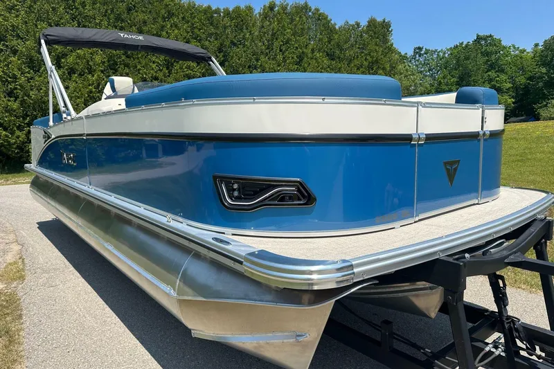 Slide: The Image of 2025 Tahoe 2585 pontoon boat with blue and white exterior on a sunny day. - 9