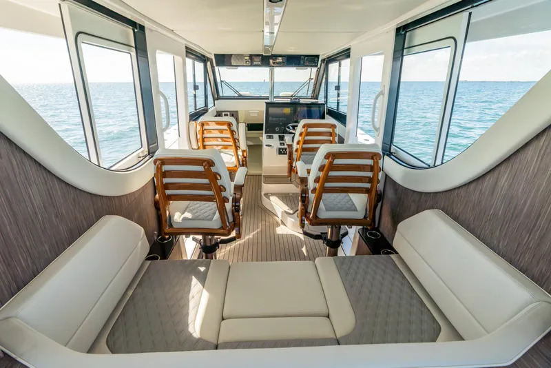 Slide: The Image of 2025 Invincible 46 Pilothouse interior with ocean view, modern seating, and navigation controls. - 15