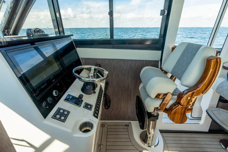 Slide: The Image of 2025 Invincible 46 Pilothouse helm station with modern controls and luxurious captain's chair. - 14