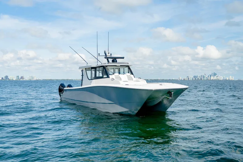 Slide: The Image of 2025 Invincible 46 Pilothouse boat on open water with city skyline in background. - 10