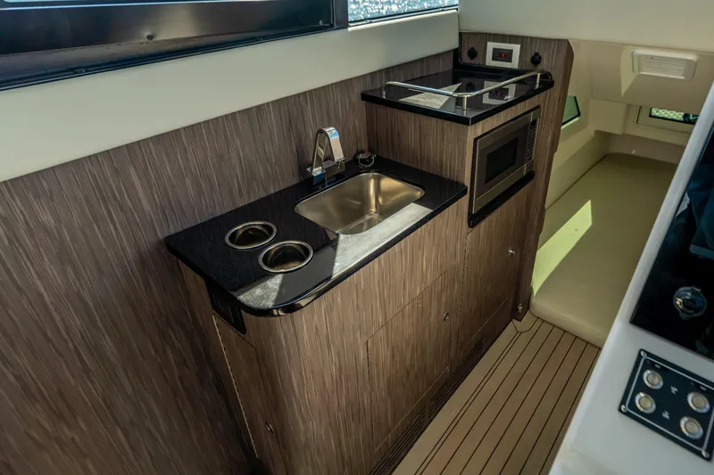 Slide: The Image of 2025 Invincible 46 Pilothouse interior kitchen with sink, stove, and microwave. - 13