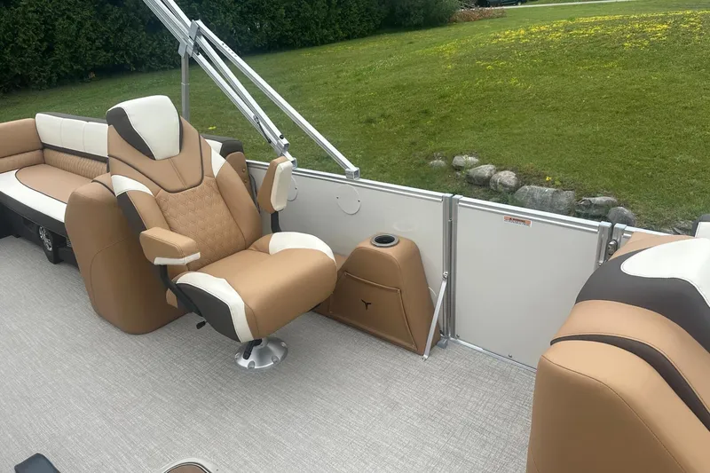 Slide: The Image of Luxurious seating on 2025 Tahoe 2585 boat, featuring tan and white upholstery, with scenic grassy backdrop. - 15