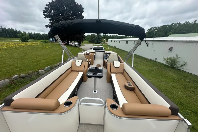 Slide: The Image of 2025 Tahoe 2585 pontoon boat with spacious seating and canopy, parked outdoors. - 18