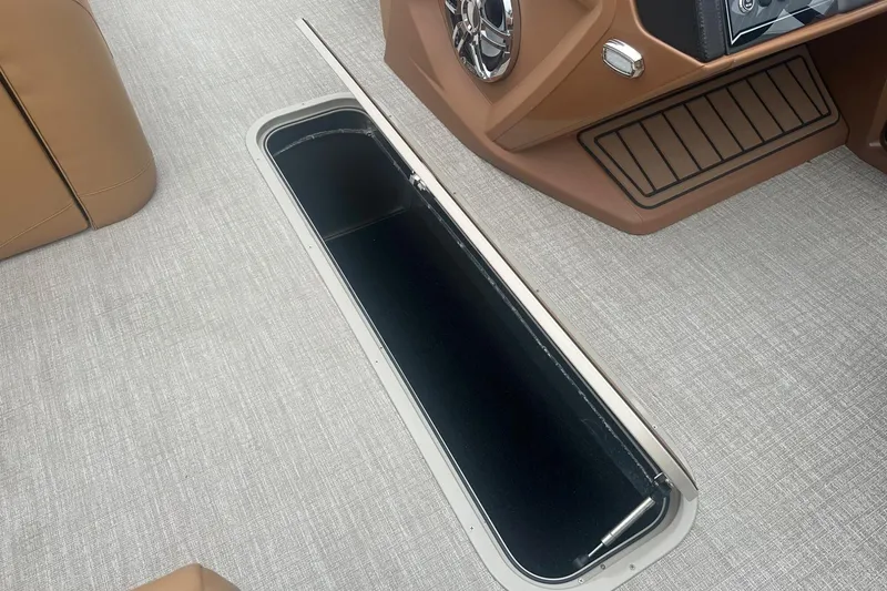 Slide: The Image of 2025 Tahoe 2585 boat interior with open storage compartment and brown seating. - 29