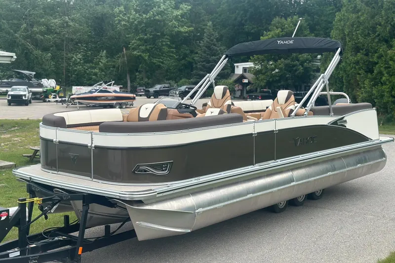 Slide: The Image of 2025 Tahoe 2585 pontoon boat on trailer, parked outdoors with trees in background. - 3