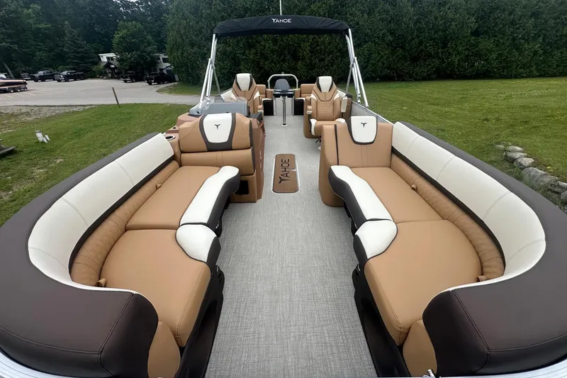 Slide: The Image of 2025 Tahoe 2585 pontoon boat with luxurious tan and white seating, set in a grassy area. - 31