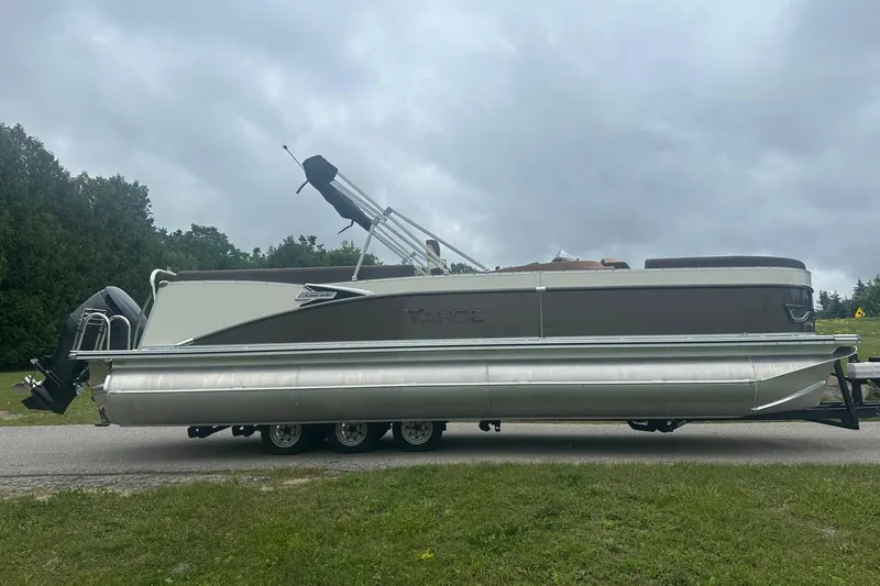 Slide: The Image of 2025 Tahoe 2585 pontoon boat on trailer, parked on roadside under cloudy sky. - 8
