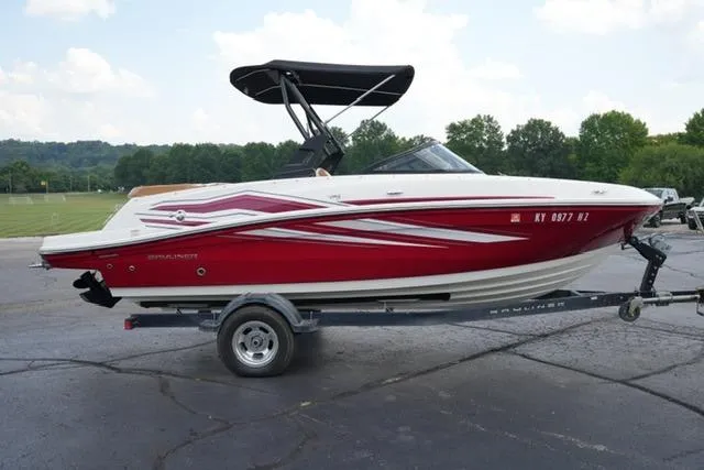 Slide: The Image of 2019 Bayliner VR5 Bowrider I/O boat on trailer, red and white design, parked outdoors. - 3