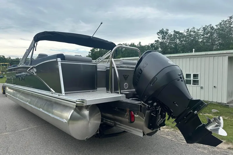 Slide: The Image of 2025 Tahoe 2585 pontoon boat with outboard motor, parked near a building. - 4