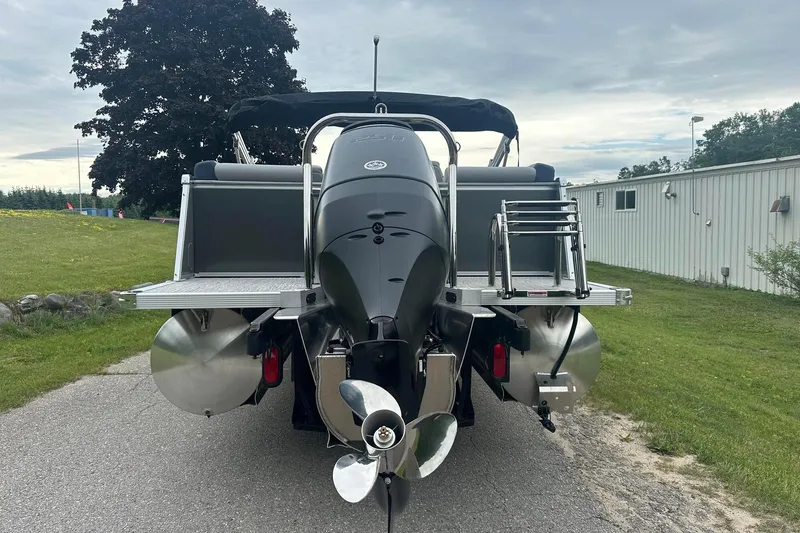 Slide: The Image of 2025 Tahoe 2585 boat rear view with outboard motor and ladder on a paved path. - 5