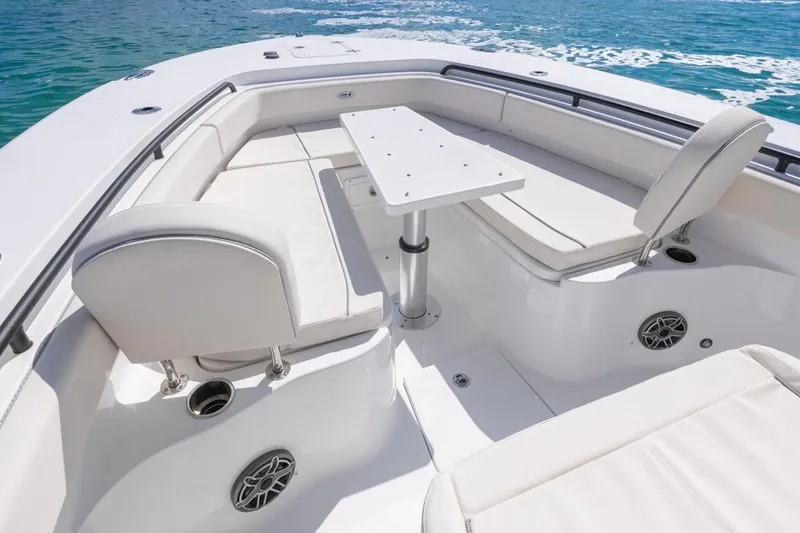 Slide: The Image of 2026 Sea Hunt Gamefish 28 Forward Seating with white cushioned seats and table on blue water. - 13