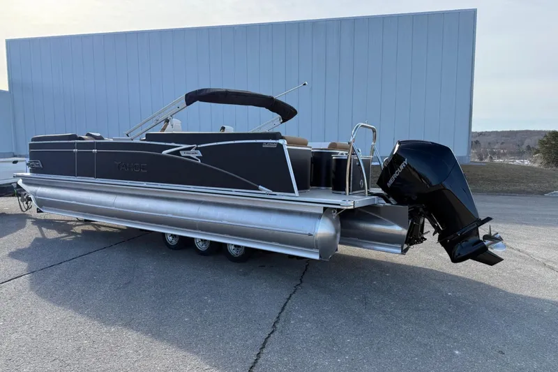 Slide: The Image of 2025 Tahoe 2585 pontoon boat with Mercury outboard engine on a sunny day. - 2