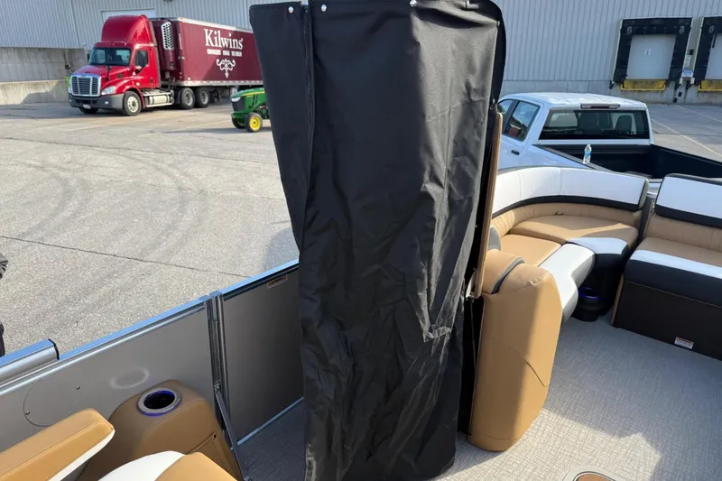 Slide: The Image of 2025 Tahoe 2585 boat interior with seating and privacy curtain, parked near trucks. - 23