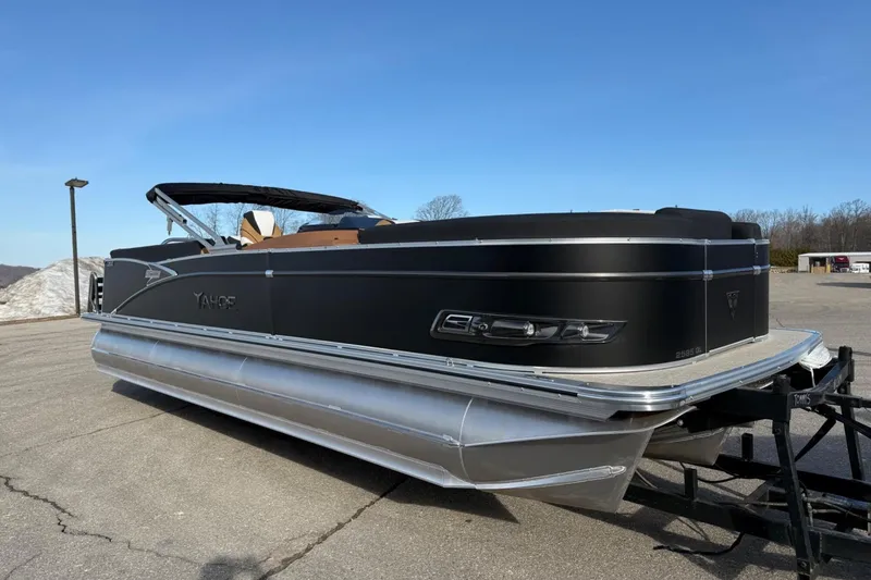 Slide: The Image of 2025 Tahoe 2585 pontoon boat on trailer, sleek black design, parked outdoors. - 6