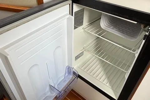 Slide: The Image of Open refrigerator inside a 1999 Tiara Yachts 2900 Coronet, showing empty shelves and door storage. - 27