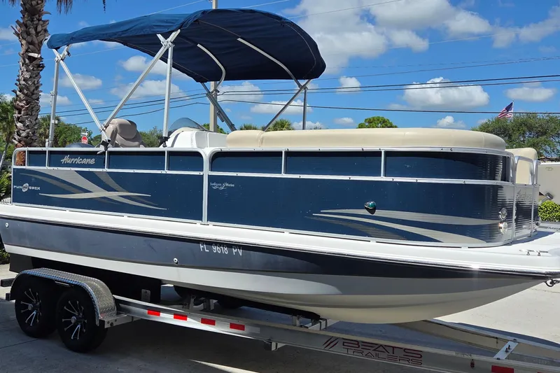 Slide: The Image of 2014 Hurricane FunDeck 216 OB boat on trailer, blue and white design, under sunny sky. - 15