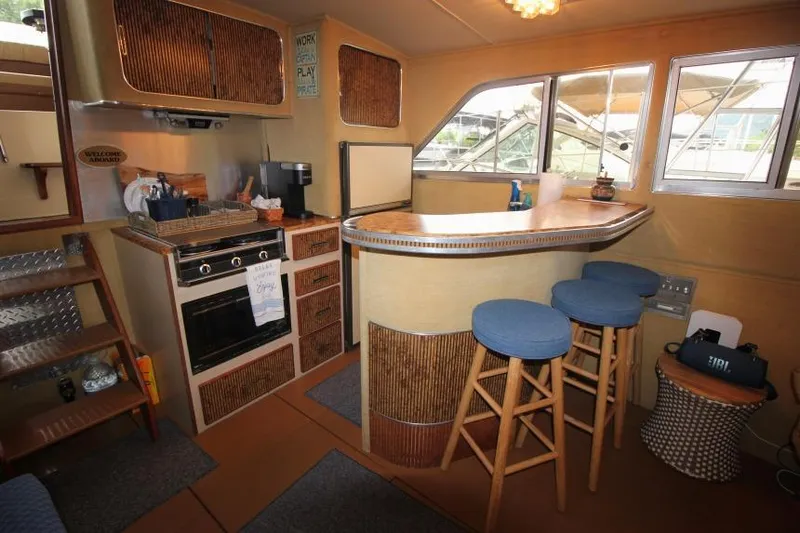 Slide: The Image of Interior of 1983 Chris-Craft 350 Catalina with kitchen and bar area, featuring stools and appliances. - 11