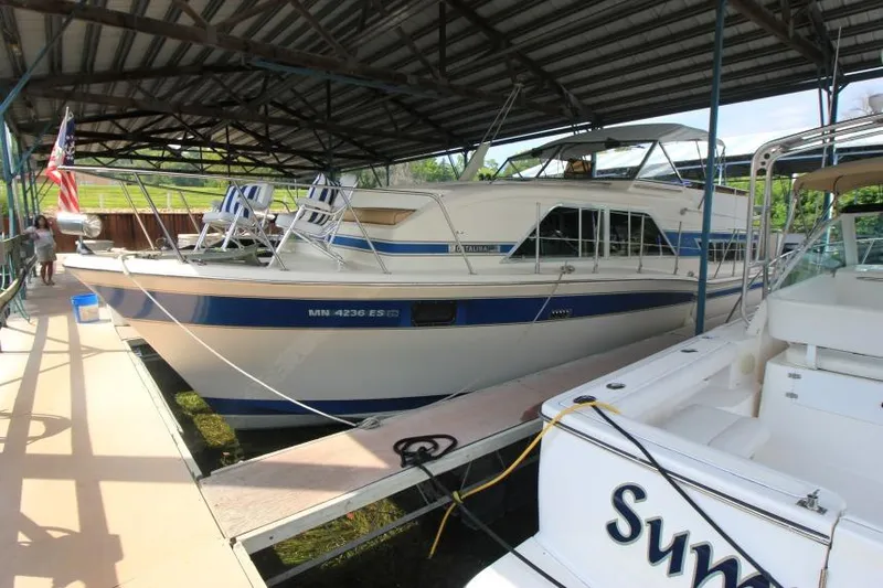 Slide: The Image of 1983 Chris-Craft 350 Catalina docked under a covered marina with striped chairs on deck. - 2