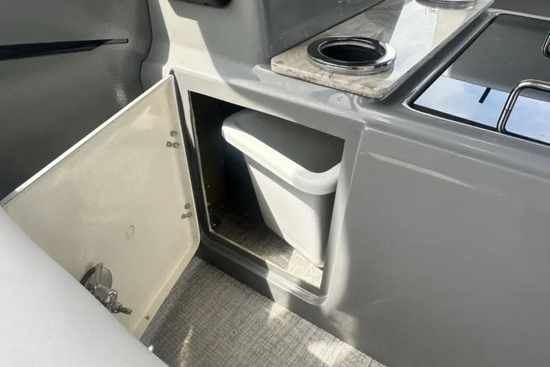 Slide: The Image of Interior of 2025 Tahoe 2785 boat with open storage compartment and trash bin. - 17