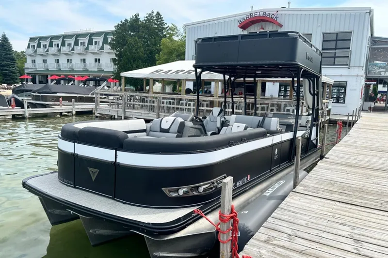 Slide: The Image of 2025 Tahoe 2785 pontoon boat docked near a waterfront restaurant. - 8