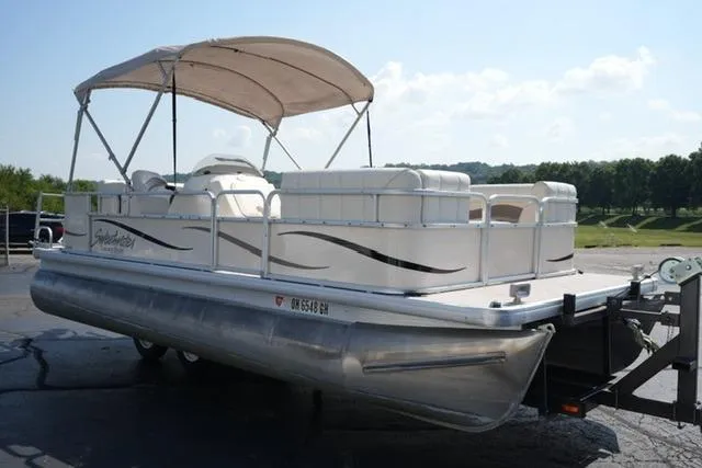Slide: The Image of 2007 Godfrey 200 Sweetwater pontoon boat with canopy on a trailer, parked outdoors. - 3