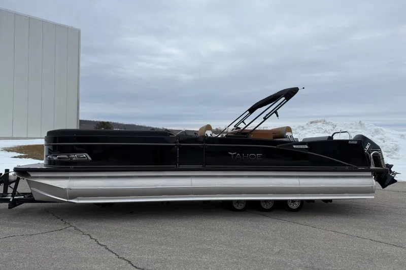 Slide: The Image of 2025 Tahoe 2785 pontoon boat with black exterior, parked on a trailer. - 1