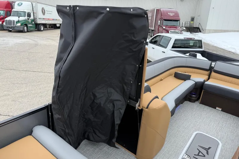 Slide: The Image of 2025 Tahoe 2785 boat interior with tan and gray seating, black privacy curtain, and outdoor setting. - 23