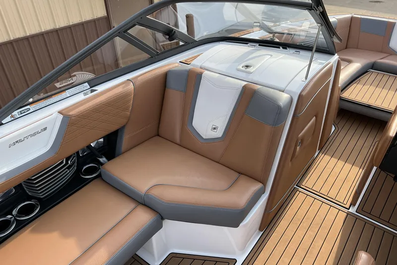 Slide: The Image of 2018 Nautique Super Air Nautique G25 interior with tan and gray seating, teak flooring. - 7