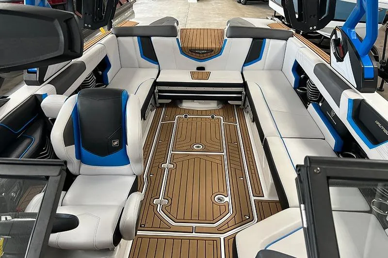 Slide: The Image of 2018 Nautique Super Air Nautique G25 interior with white and blue seating, teak flooring. - 4