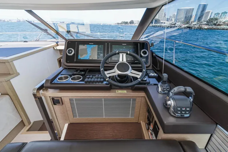 Slide: The Image of Helm of 2019 Prestige 520 yacht with navigation system, steering wheel, and city skyline view. - 15