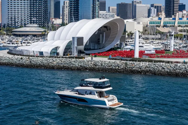 Slide: The Image of Prestige 520 yacht cruising near modern waterfront architecture, city skyline in background, 2019 model. - 2