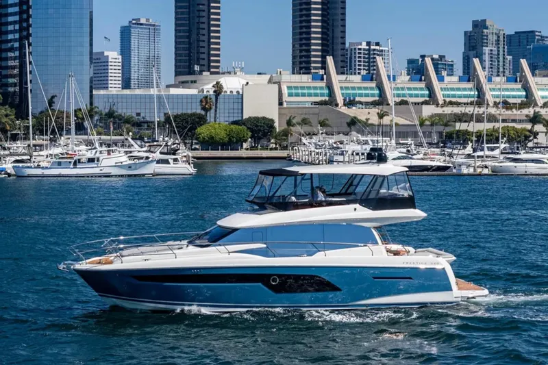 Slide: The Image of 2019 Prestige 520 yacht cruising in a marina with city skyline backdrop. - 33