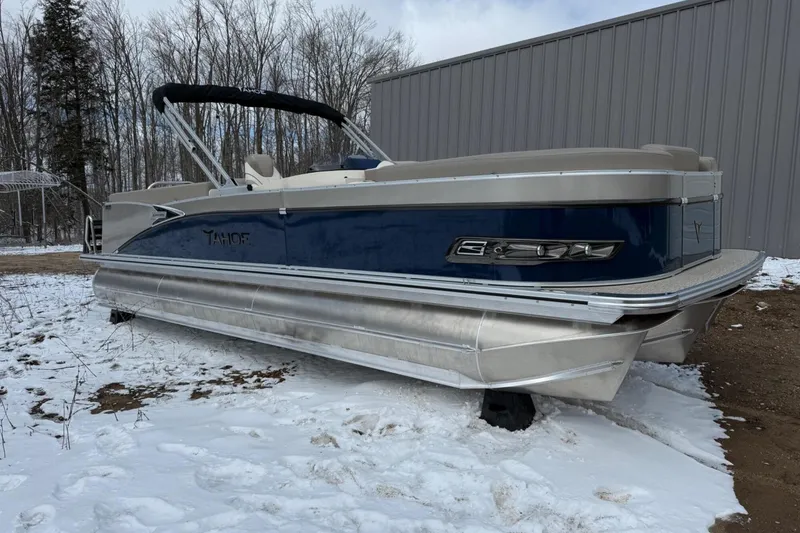 Slide: The Image of 2025 Tahoe 2585 pontoon boat on snowy ground near a metal building. - 2