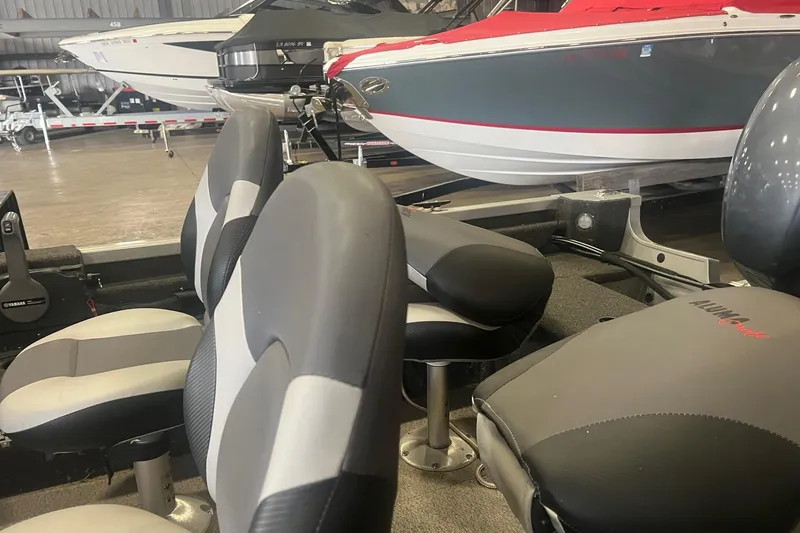 Slide: The Image of 2017 Alumacraft 165 boat interior with gray and black seating in a showroom. - 4