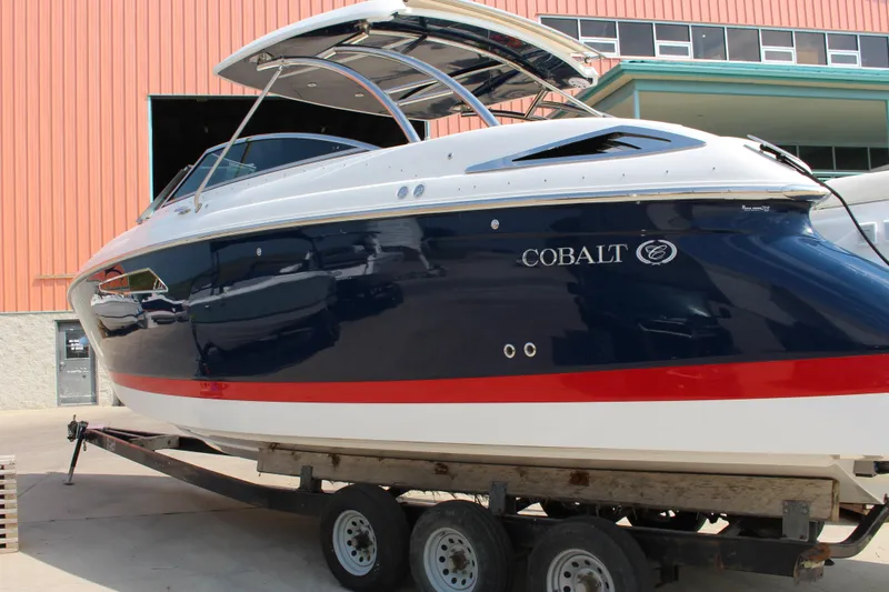 Slide: The Image of 2017 Cobalt R35 boat on trailer, blue and white with red stripe, docked outdoors. - 39