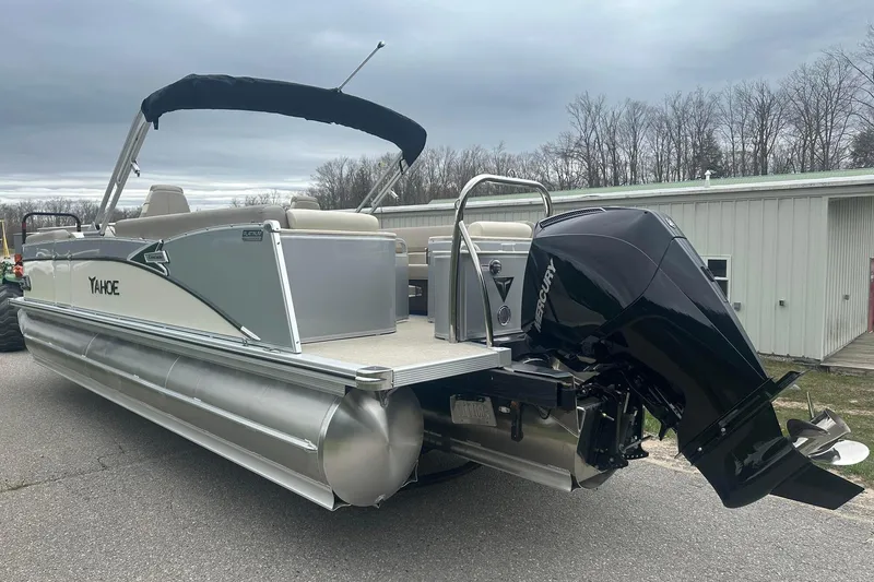 Slide: The Image of 2025 Tahoe 2585 pontoon boat with Mercury outboard motor, parked outdoors. - 2