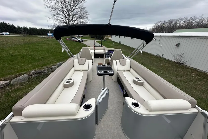 Slide: The Image of 2025 Tahoe 2585 pontoon boat with beige seating and black canopy on a grassy area. - 9