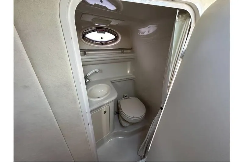 Slide: The Image of Compact bathroom in 2007 Sea Ray 270 Amberjack boat, featuring sink, toilet, and porthole window. - 12