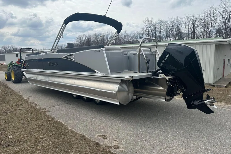 Slide: The Image of 2025 Tahoe 2585 pontoon boat with Mercury outboard motor on a trailer. - 2