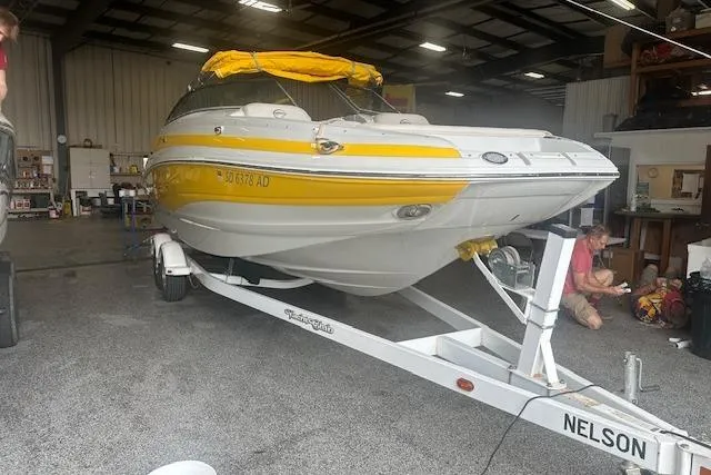 Slide: The Image of 2015 Crownline E6 boat with yellow accents on a trailer in a garage. - 0