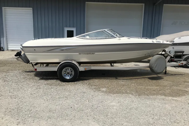 Slide: The Image of 2005 Stingray 195 LR boat on trailer, parked outside a building. - 4