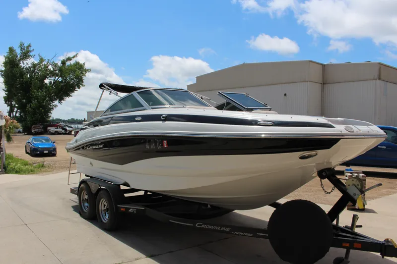 The Image of 2013 Crownline E1 boat on trailer, parked outdoors under blue sky. - 1