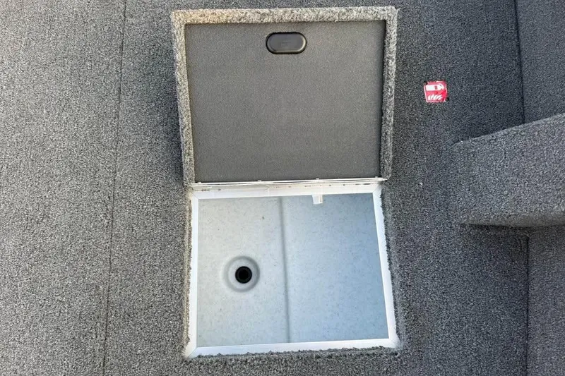 Slide: The Image of Open storage compartment on 2026 Crestliner 1850 Pro Tiller boat, featuring carpeted interior. - 11