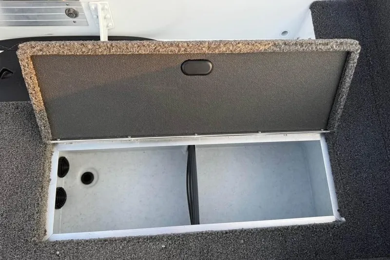 Slide: The Image of Open storage compartment in 2026 Crestliner 1850 Pro Tiller boat, featuring carpeted lid. - 12