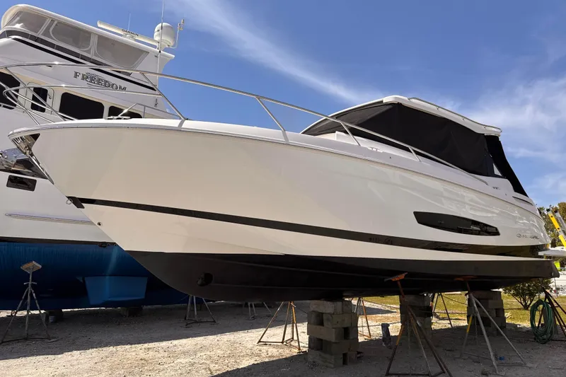 Slide: The Image of 2022 Regal 36 XO boat on stands, white hull, black canopy, clear blue sky background. - 2