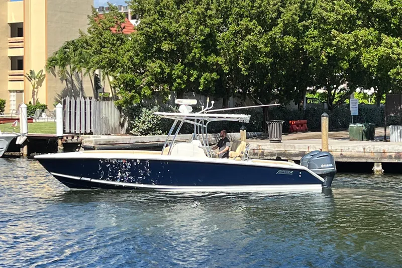 Slide: The Image of 2012 Jupiter 29 FS CC boat on water near dock, surrounded by trees. - 2