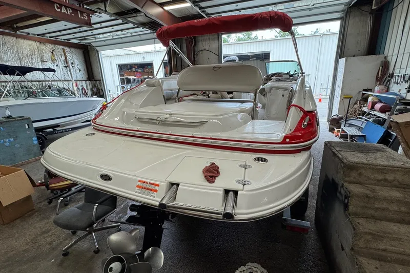 Slide: The Image of 2011 Crownline 252 EX boat in a workshop, rear view with red accents. - 3